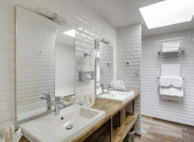 Appartement salle de bain avec deux lavabos et deux miroirs à l’hôtel George