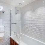 Appartement salle de bain avec des carreaux blancs et une baignoire à l’hôtel George