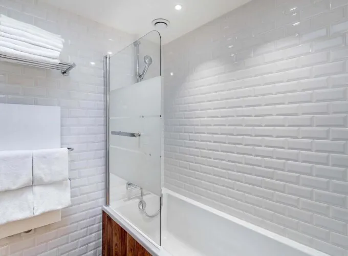 Appartement salle de bain avec des carreaux blancs et une baignoire à l’hôtel George
