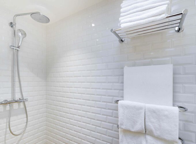 Appartement salle de bain avec des carreaux blancs et une pomme de douche à l’hôtel George