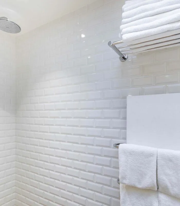 Appartement salle de bain avec des carreaux blancs et une pomme de douche à l’hôtel George
