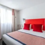 Chambre Communicante avec une tête de lit rouge et des oreillers rouges à l’hôtel George