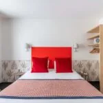 Chambre Communicante avec une tête de lit rouge et des oreillers rouges à l’hôtel George
