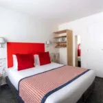Chambre Communicante avec une tête de lit rouge et des oreillers rouges à l’hôtel George