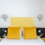Chambre Communicante avec une tête de lit jaune et des oreillers jaunes à l’hôtel George