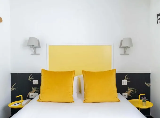 Chambre Communicante avec une tête de lit jaune et des oreillers jaunes à l’hôtel George