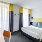 Chambre Familiale avec rideaux jaunes et un lit à l’hôtel George