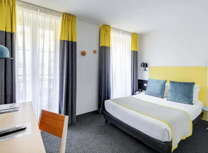 Chambre Familiale avec rideaux jaunes et un lit à l’hôtel George