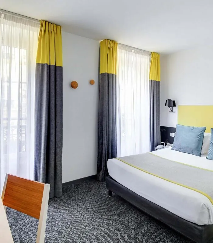 Chambre Familiale avec rideaux jaunes et un lit à l’hôtel George