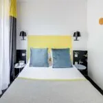 Chambre Familiale avec rideaux jaunes et un lit à l’hôtel George