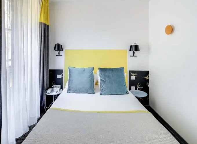 Chambre Familiale avec rideaux jaunes et un lit à l’hôtel George
