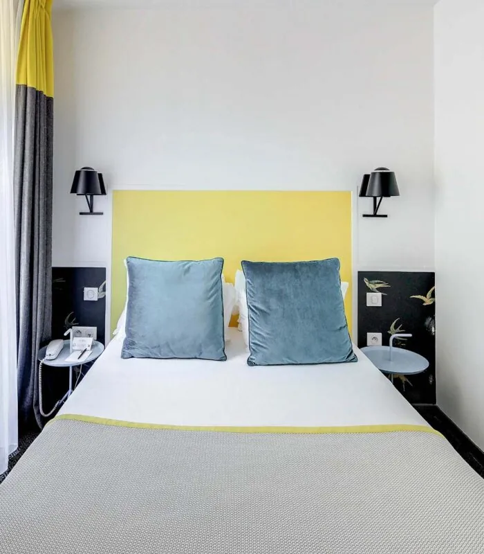 Chambre Familiale avec rideaux jaunes et un lit à l’hôtel George