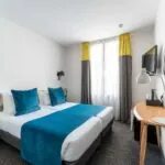 Chambre Familiale avec deux lits et un bureau à l’hôtel George