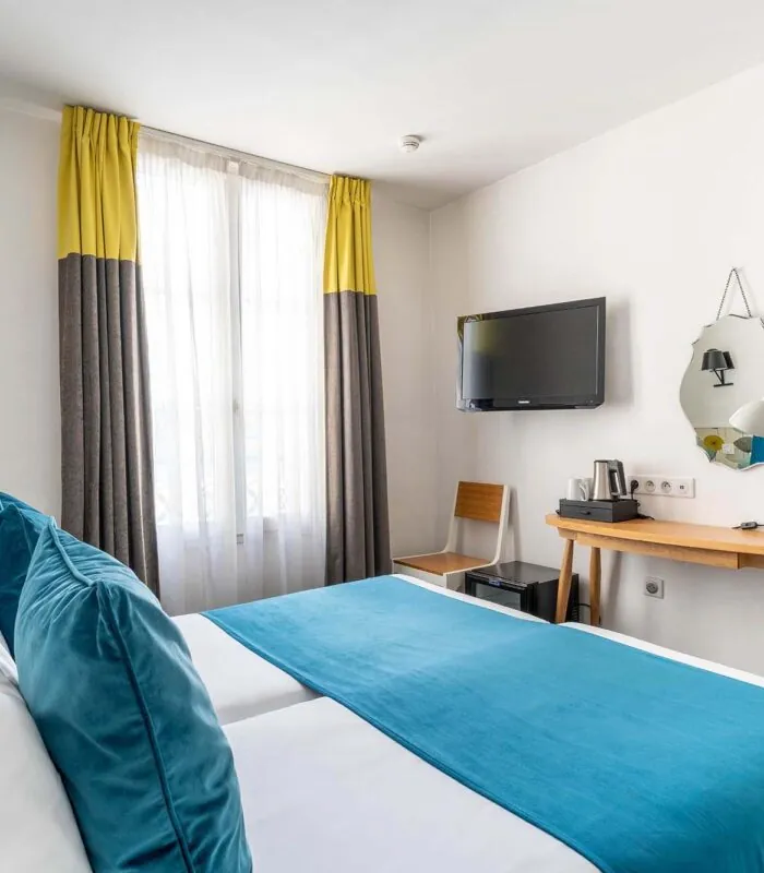 Chambre Familiale avec deux lits et un bureau à l’hôtel George