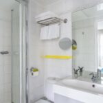 Chambre Familiale salle de bain avec un lavabo, un miroir et une douche à l’hôtel George
