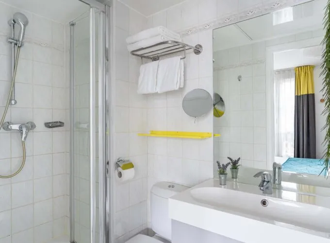 Chambre Familiale salle de bain avec un lavabo, un miroir et une douche à l’hôtel George