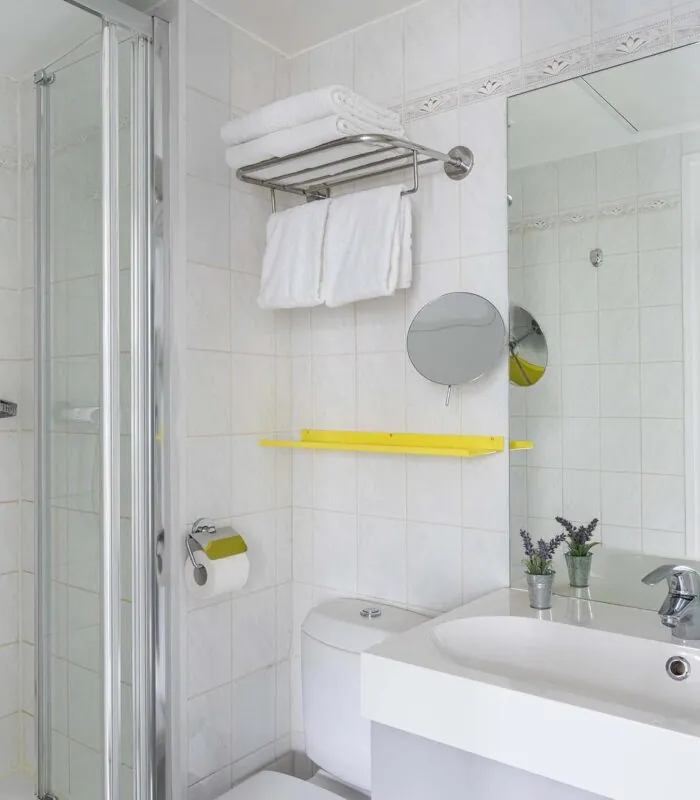 Chambre Familiale salle de bain avec un lavabo, un miroir et une douche à l’hôtel George