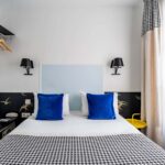 Chambre Single avec un lit, des oreillers bleus et une couverture à carreaux noir et blanc à l’Hôtel George