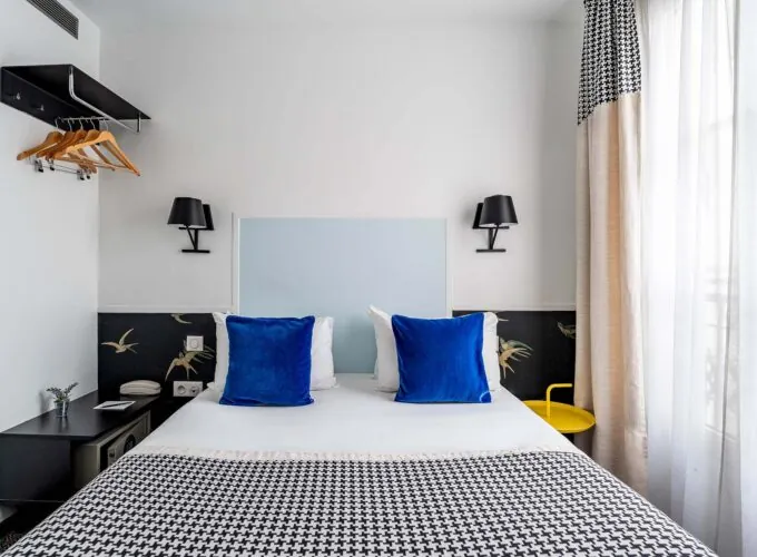Chambre Single avec un lit, des oreillers bleus et une couverture à carreaux noir et blanc à l’Hôtel George