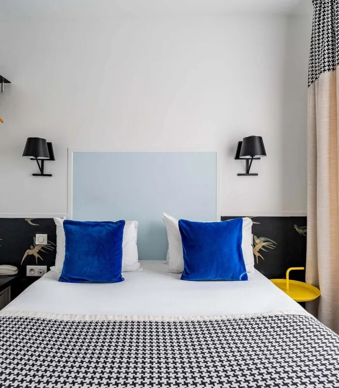 Chambre Single avec un lit, des oreillers bleus et une couverture à carreaux noir et blanc à l’Hôtel George