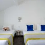 Chambre Triple Terrasse avec deux lits, des oreillers bleus et un oreiller avec une chouette à l’Hôtel George