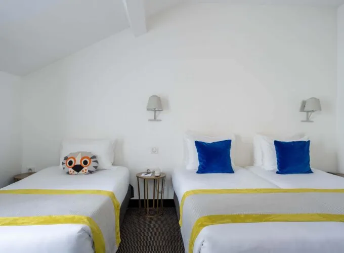 Chambre Triple Terrasse avec deux lits, des oreillers bleus et un oreiller avec une chouette à l’Hôtel George