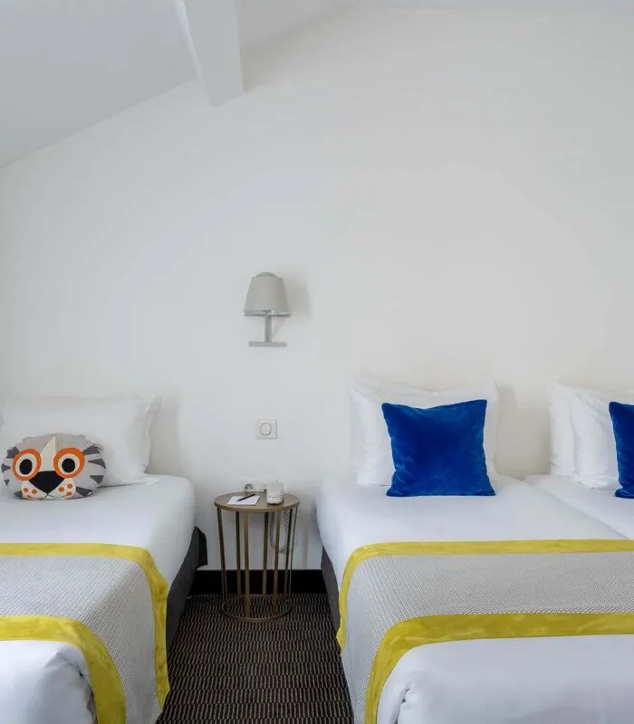 Chambre Triple Terrasse avec deux lits, des oreillers bleus et un oreiller avec une chouette à l’Hôtel George