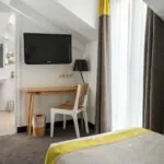 Chambre Triple Terrasse avec un bureau, une chaise et une télévision à écran plat à l’Hôtel George