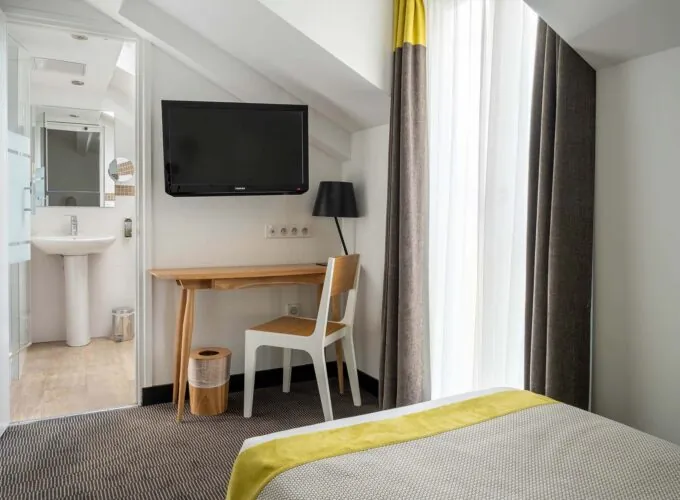 Chambre Triple Terrasse avec un bureau, une chaise et une télévision à écran plat à l’Hôtel George