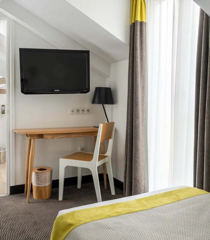 Chambre Triple Terrasse avec un bureau, une chaise et une télévision à écran plat à l’Hôtel George