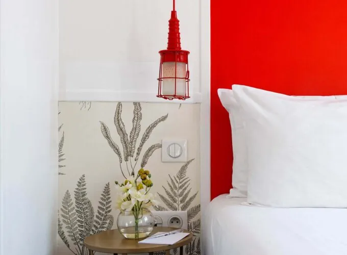 Chambre Twin avec une table de chevet et un vase de fleurs dessus à l’Hôtel George