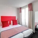 Chambre Twin avec deux lits et une tête de lit rouge à l’Hôtel George
