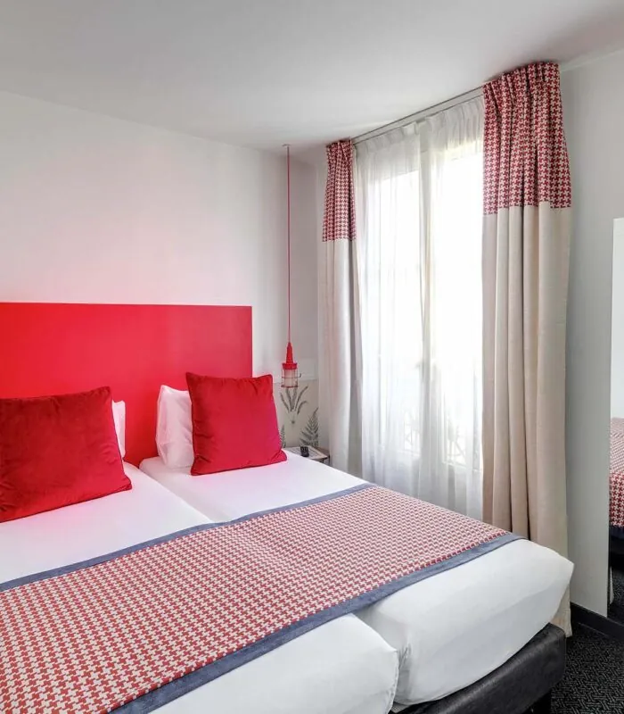 Chambre Twin avec deux lits et une tête de lit rouge à l’Hôtel George