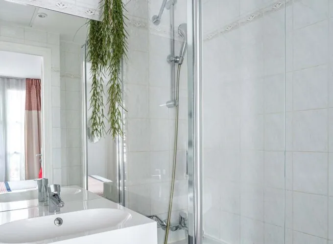 Salle de bain de la Chambre Twin avec un lavabo, une douche et un miroir à l’Hôtel George