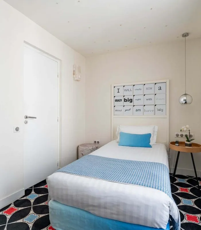 Chambre Communicante à l’hôtel Joke avec un lit simple et une enseigne sur le mur