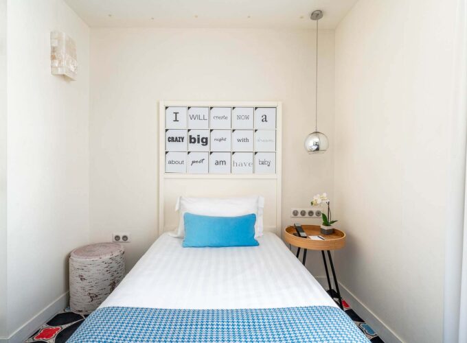 Chambre Communicante à l’hôtel Joke avec un lit simple et une enseigne sur le mur