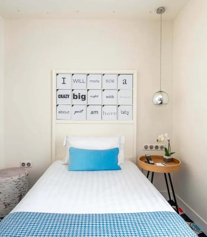 Chambre Communicante à l’hôtel Joke avec un lit simple et une enseigne sur le mur