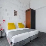 Appartement chambre à l’hôtel Joyce avec deux lits et une horloge sur le mur