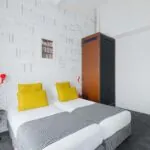 Appartement chambre à l’hôtel Joyce avec deux lits et une horloge sur le mur