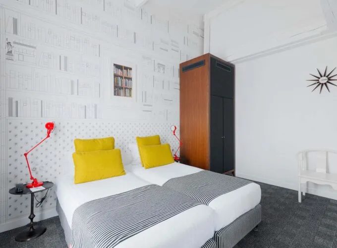 Appartement chambre à l’hôtel Joyce avec deux lits et une horloge sur le mur