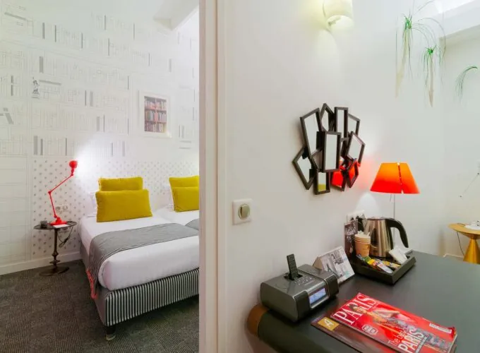Appartement à l’hôtel Joyce avec un lit et un bureau sur lequel se trouve un magazine Paris