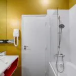 Appartement salle de bain à l’hôtel Joyce avec un mur jaune et une porte blanche