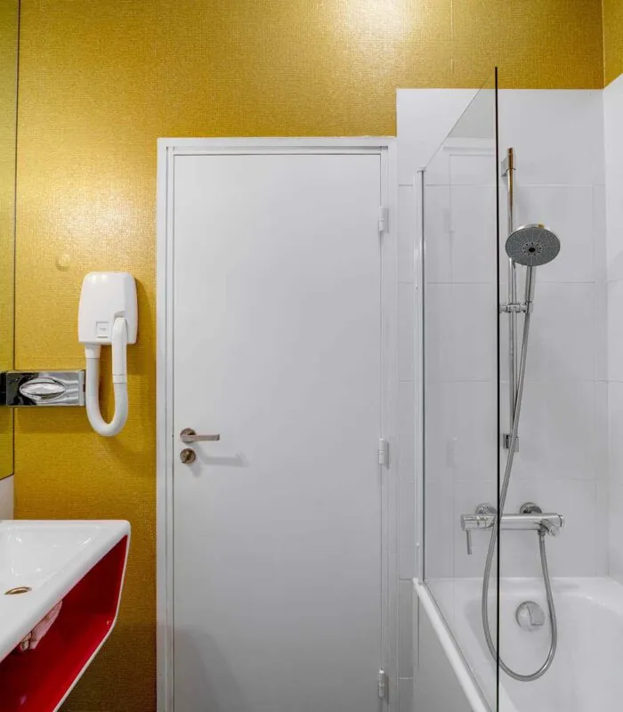 Appartement salle de bain à l’hôtel Joyce avec un mur jaune et une porte blanche
