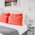 Chambre Communicante à l’hôtel Joyce avec un lit, des oreillers rouges et une couverture rayée