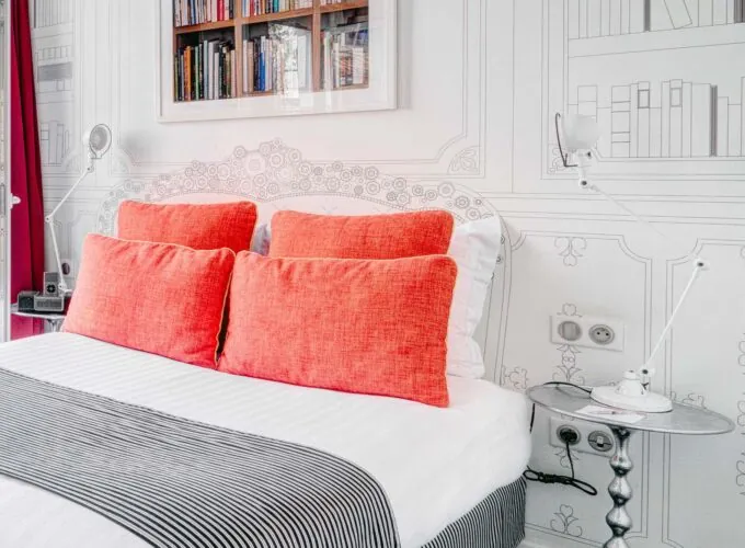 Chambre Communicante à l’hôtel Joyce avec un lit, des oreillers rouges et une couverture rayée