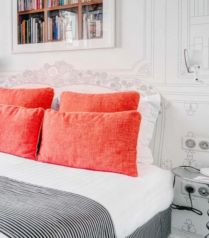 Chambre Communicante à l’hôtel Joyce avec un lit, des oreillers rouges et une couverture rayée