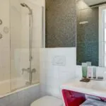 Salle de bain de la Chambre Communicante à l’hôtel Joyce avec une baignoire, un lavabo et un miroir