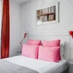 Chambre Double à l’hôtel Joyce avec un lit, des oreillers roses et une image accrochée au mur au-dessus