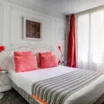 Chambre Familiale à l’hôtel Joyce avec des oreillers roses et des rideaux rouges