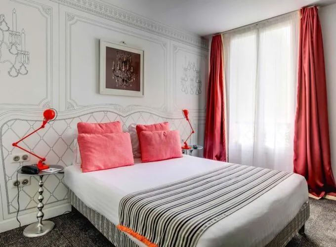 Chambre Familiale à l’hôtel Joyce avec des oreillers roses et des rideaux rouges